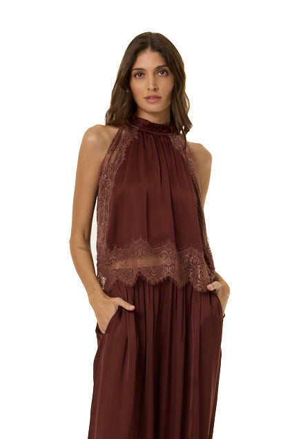 A woman modeling a sleeveless high-neck top in deep burgundy with matching lace trim at the bust and waist, shown against a plain white background.