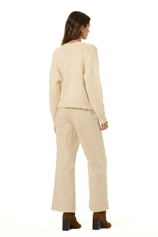 A woman shown from the back wearing a cream-colored knit sweater and matching wide-leg trousers, paired with brown ankle boots, against a plain white background.