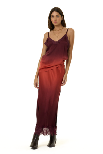 A woman modeling a long satin slip cami and skirt set with a vertical ombré color transition from deep burgundy to rust red, featuring lace trim at the neckline and hem, paired with black ankle boots against a plain white background.
