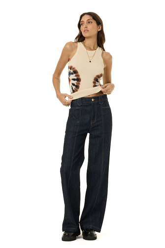 A woman modeling a sleeveless beige sweater tank top with a large brown and black graphic print on the front, paired with dark blue wide-leg jeans and black shoes, against a plain white background.