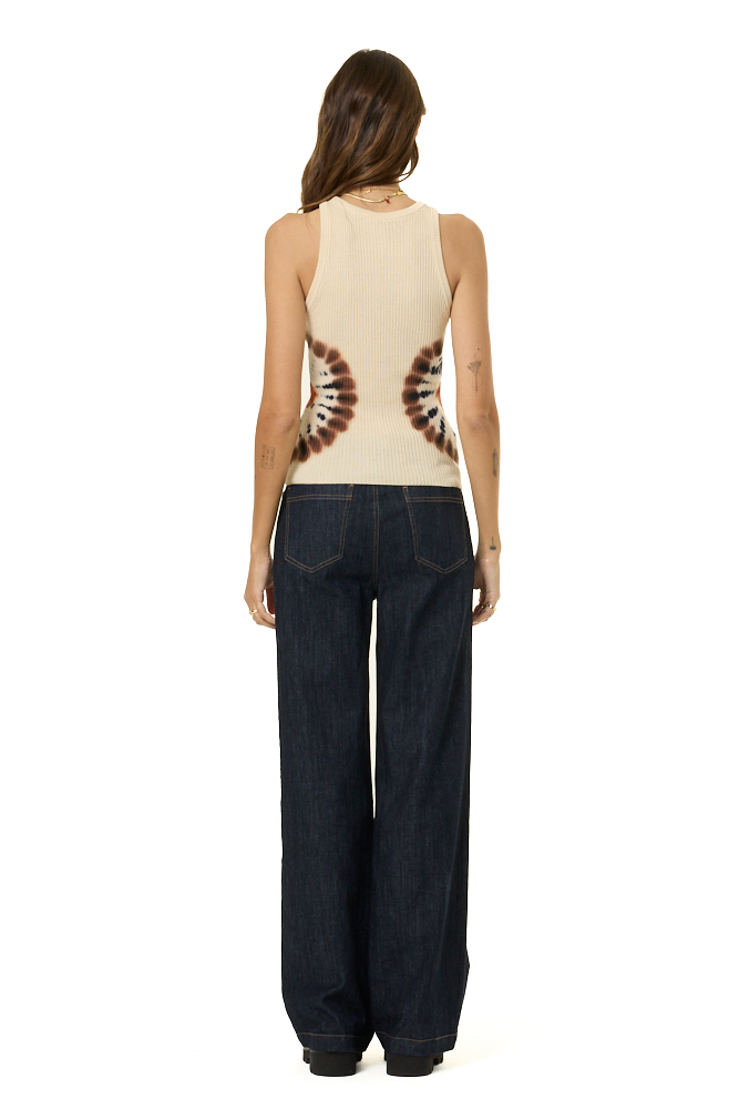 A woman shown from the back wearing a sleeveless cream sweater tank top with a brown and white spiral pattern on the back, paired with dark wide-leg jeans, against a plain white background.