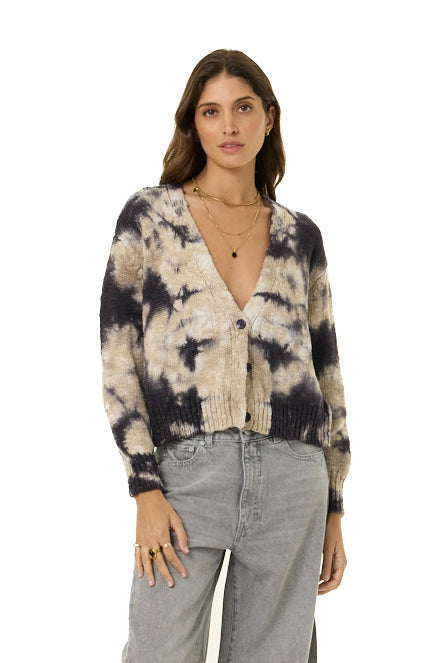A woman modeling a tie-dye knit cardigan with a deep V-neck and button front, paired with light gray jeans, against a plain white background.