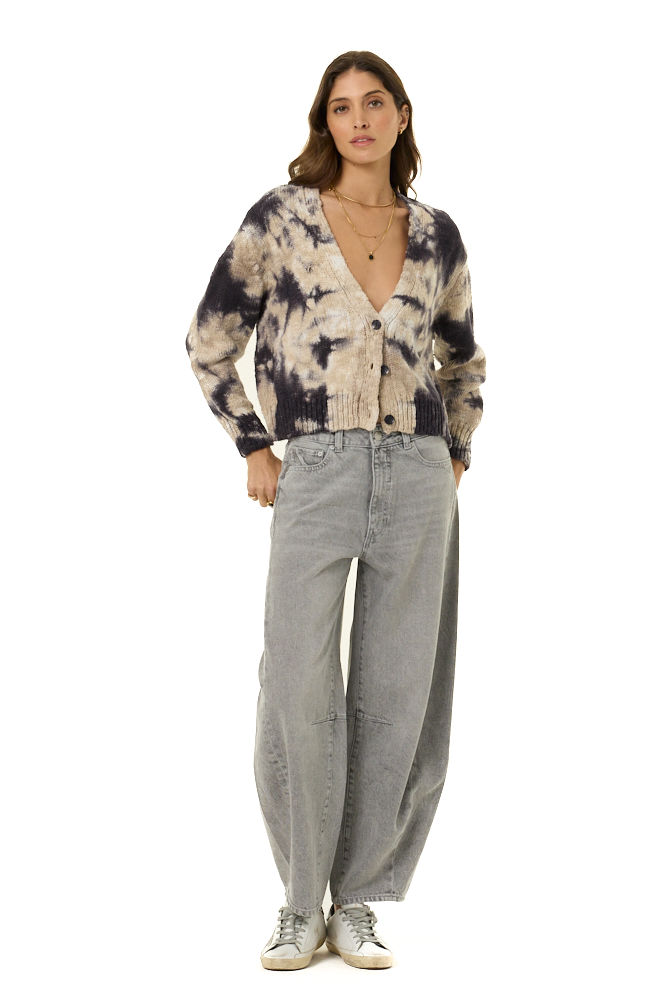 A woman modeling a tie-dye knit cardigan with a V-neck and button front, paired with wide-leg light gray jeans and white sneakers, against a plain white background.