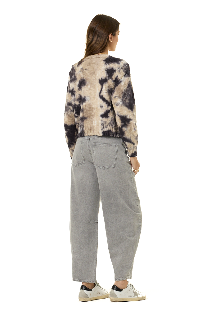 A woman shown from the back wearing a beige and black tie-dye knit cardigan, light gray wide-leg jeans, and white sneakers against a plain white background.