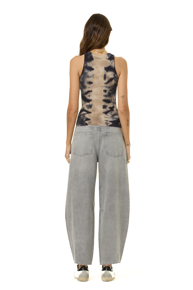 A woman shown from the back wearing a sleeveless top with a black and beige tie-dye pattern and wide-leg light gray jeans, standing against a plain white background.