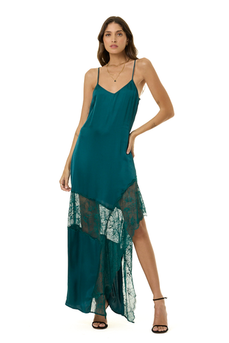 A woman modeling a teal green slip dress with spaghetti straps, a V-neckline, and a sheer lace overlay at the hem, paired with black strappy heels against a plain white background.