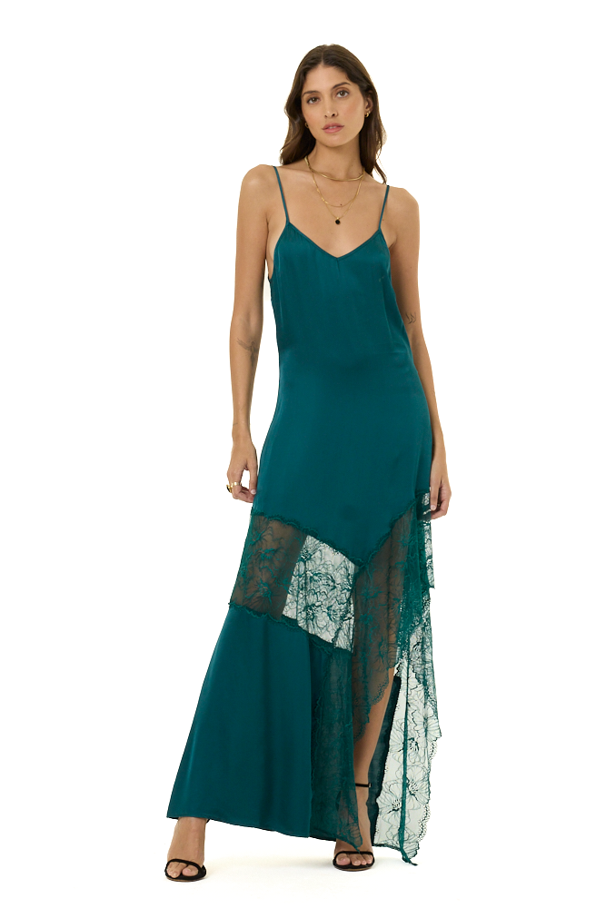 A woman modeling a teal green maxi slip dress with spaghetti straps, a V-neckline, and a layered ruffle hem featuring sheer lace panels, set against a plain white background.