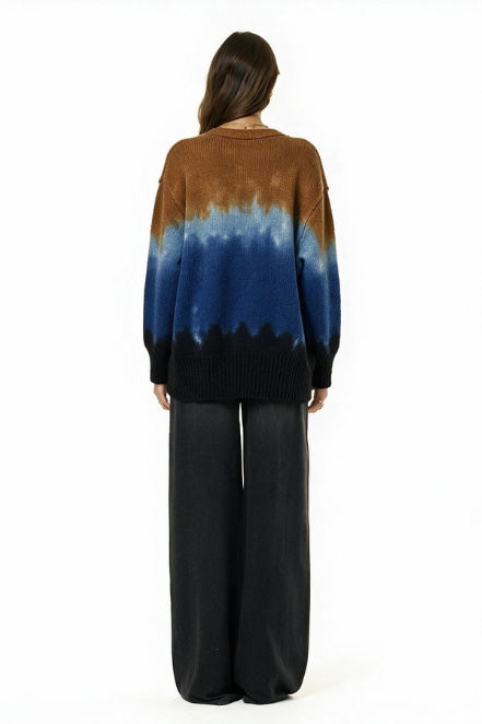 A woman viewed from behind wearing a knit sweater with a brown-to-blue tie-dye style gradient and black lower section, paired with black wide-leg pants, against a plain white background.