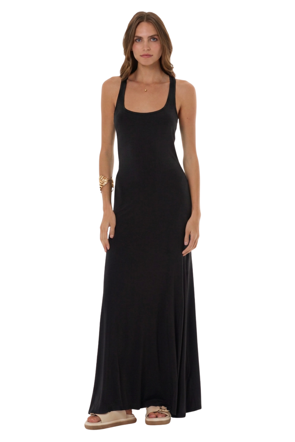A woman modeling a sleeveless black maxi dress with a scoop neckline and halter-style straps, standing against a plain white background.