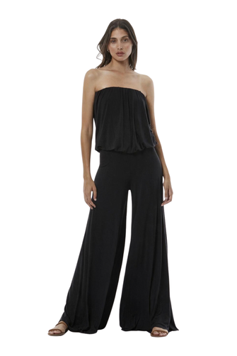 A woman modeling a black strapless jumpsuit, shown against a plain white studio background.