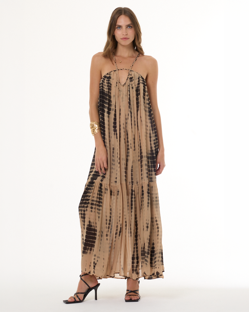 ADA compliant: Shop the Dress collection. Woman wearing a chiffon flowy tan and black dress with a white background.