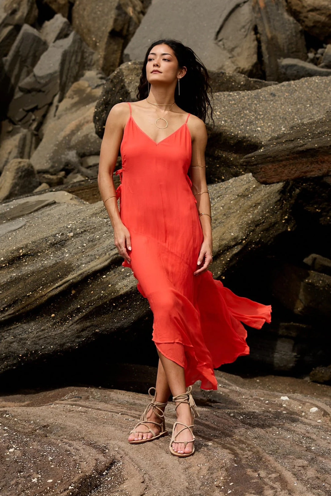 Woman in a orange/red dress standing on rocky terrain