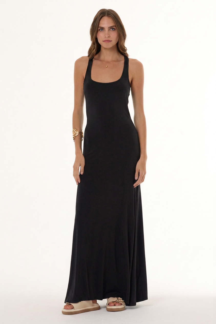 A woman modeling a sleeveless black maxi dress with a scoop neckline and halter-style straps, standing against a plain white studio background.