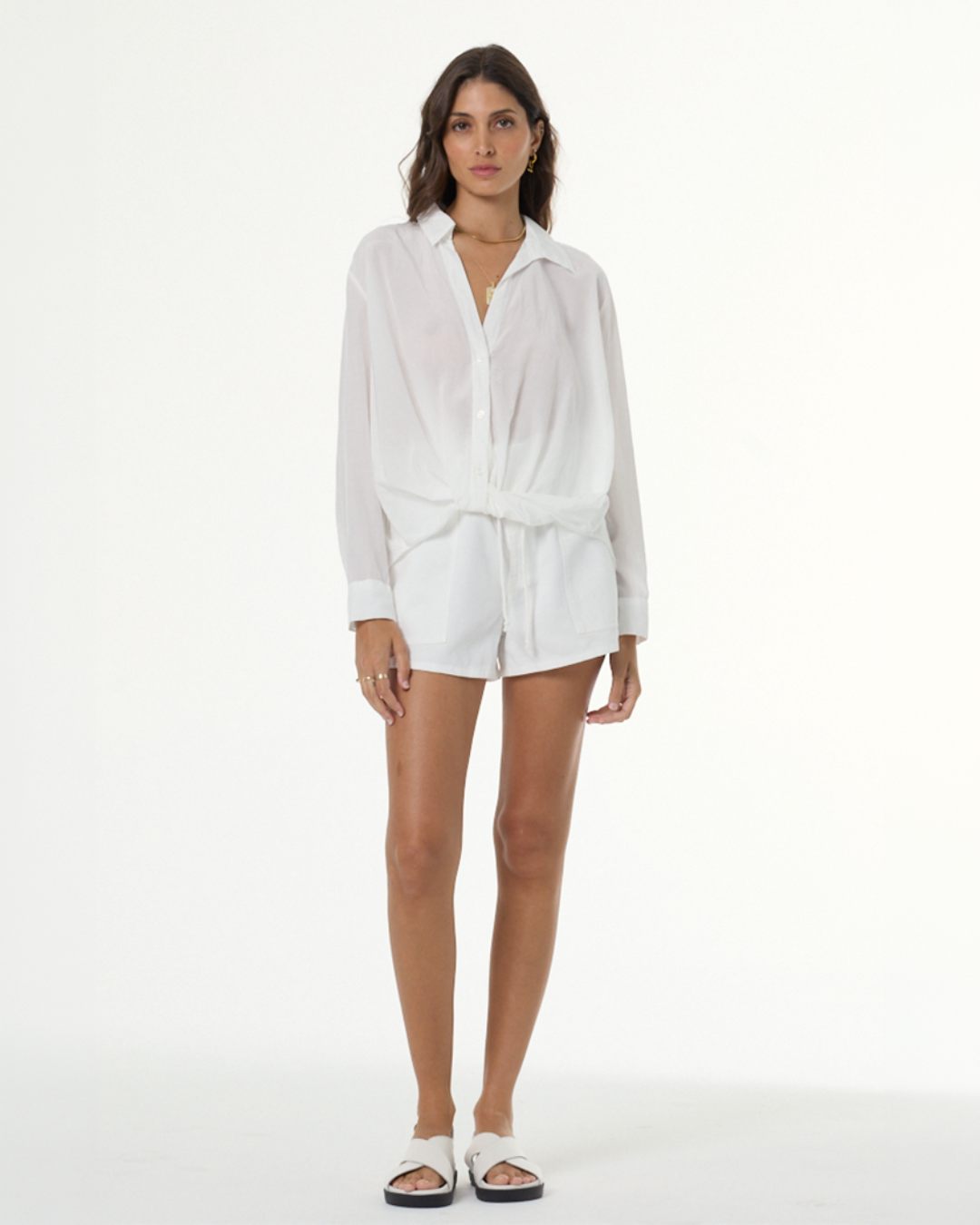 ADA compliant: Shop Tops collection. Woman wearing a white button up loose and airy top with white shorts.