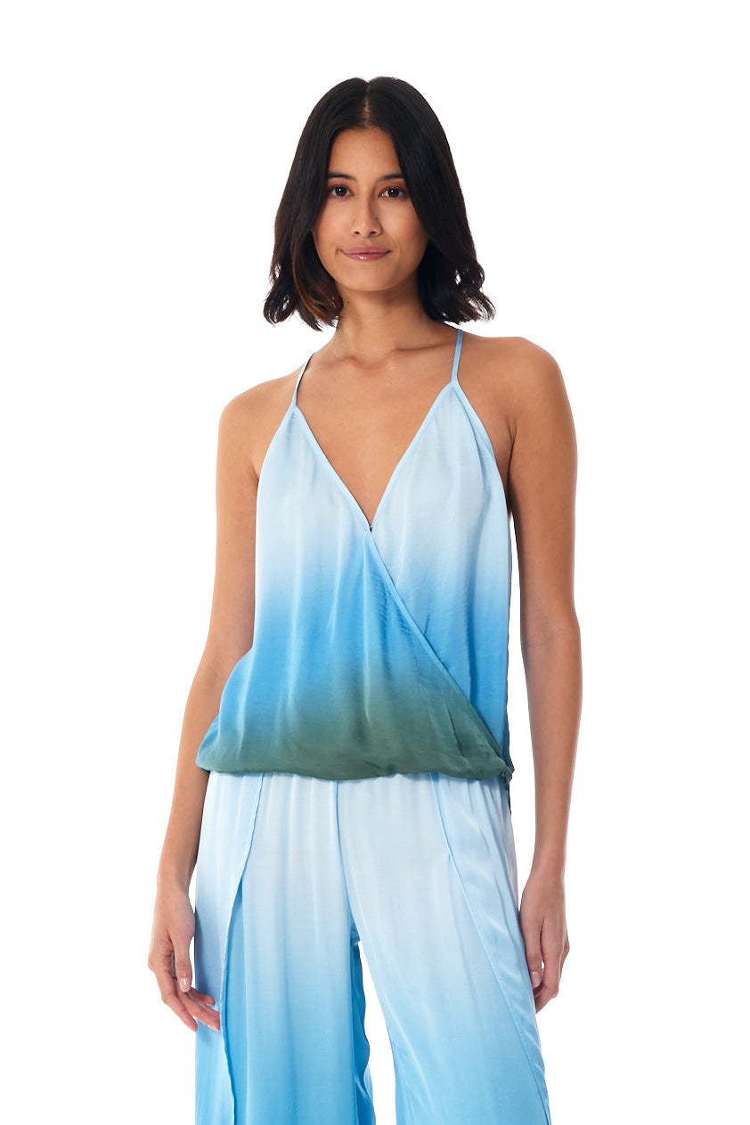 A woman modeling a sleeveless wrap-style top and matching wide-leg pants in a light blue to green ombre gradient, photographed against a plain white background.