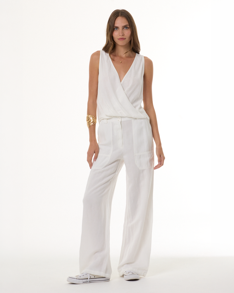 ADA compliant: Shop the Bottoms collection. Woman wearing a white sleeveless cross over blouse with white linen pants.